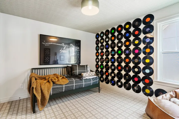 White walls with a textured ceiling, featuring a large framed wall art piece and a wall adorned with decorative vinyl records