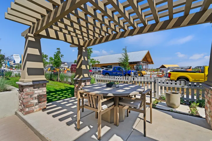 Outdoor patio featuring a slatted pergola, concrete flooring, and stone-clad support columns