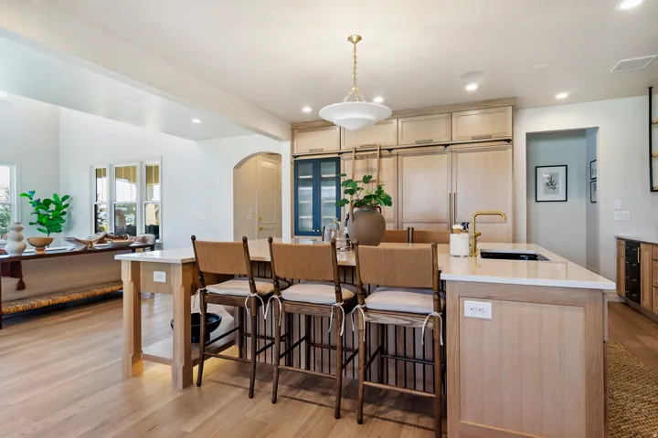 Gourmet kitchen featuring a substantial island with seating, a gold-finish faucet, and an integrated sink