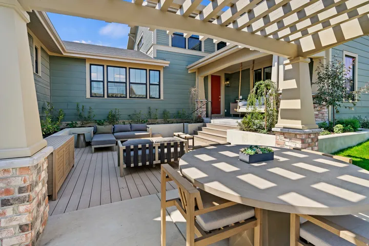 Expansive outdoor living area featuring a multi-level deck, a pergola, and a covered porch with steps