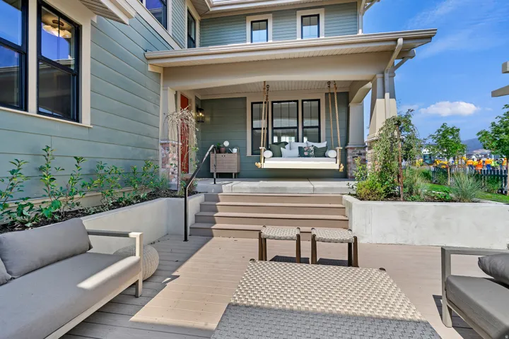 Exterior deck area featuring composite decking, a built-in planter with established greenery, and a black metal handrail leading to a covered front porch