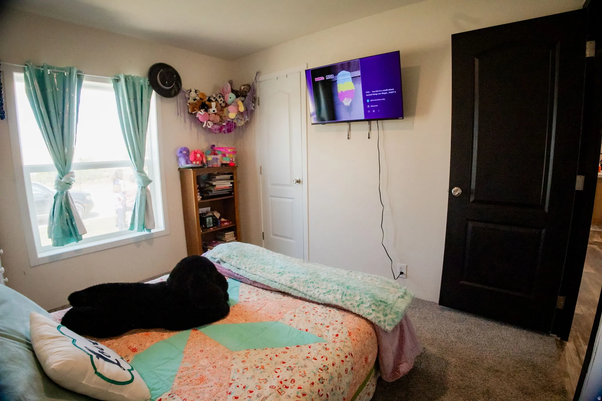 Bedroom featuring a double-pane window with white trim, light gray wall paint, dark wood-finish interior doors, and gray carpeting