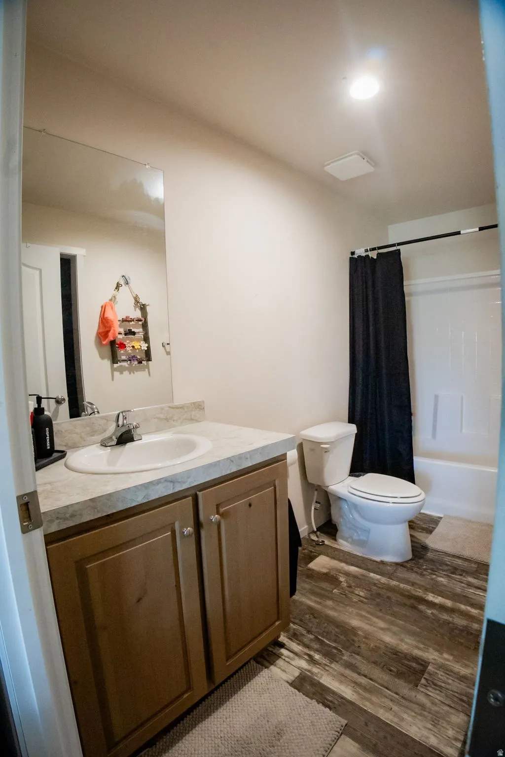 Bathroom featuring a single vanity with wood-finish cabinetry, a drop-in sink, and a laminate countertop