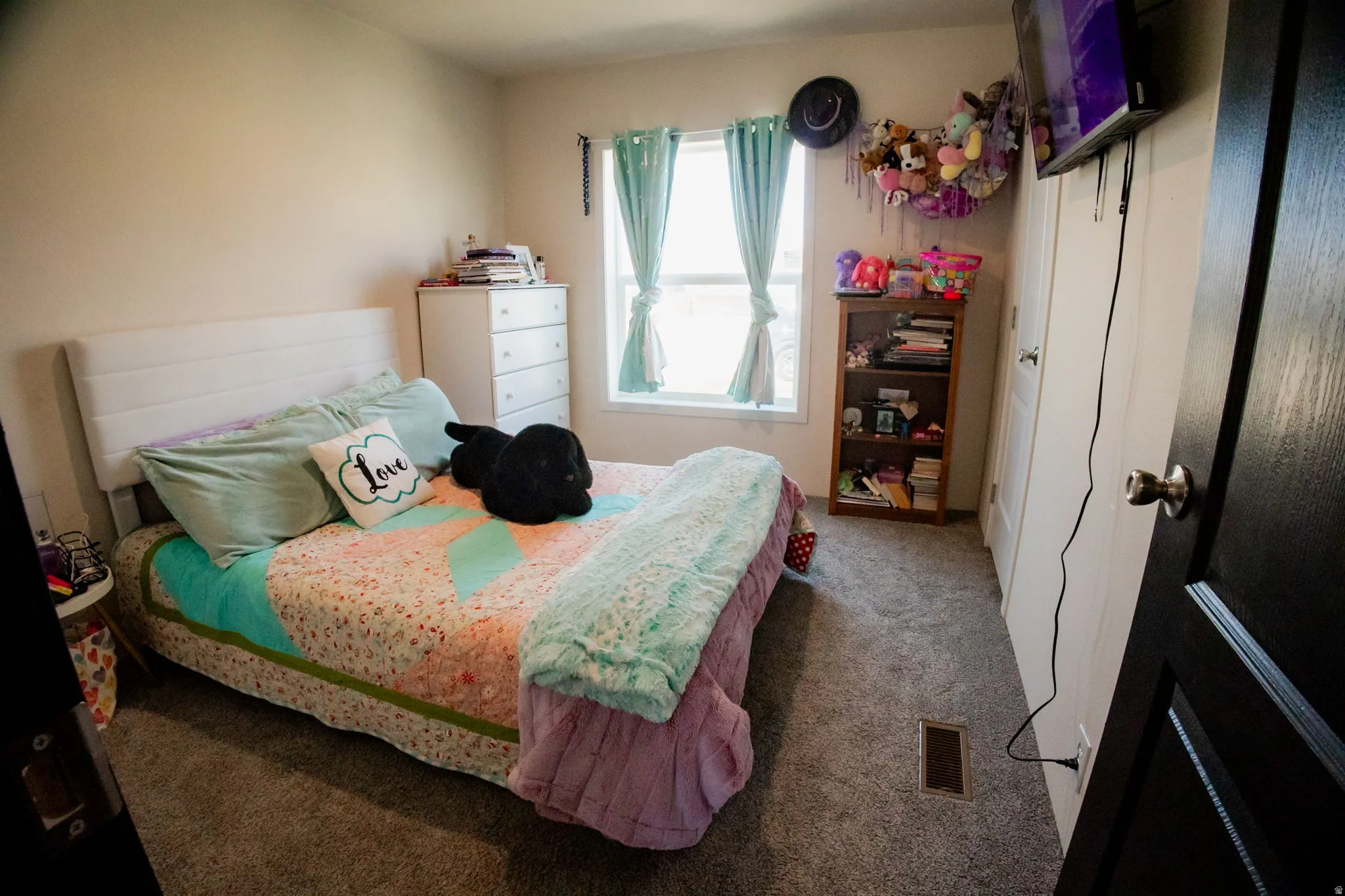 Carpeted bedroom featuring a light-colored wall, a window with natural light, and a white interior door