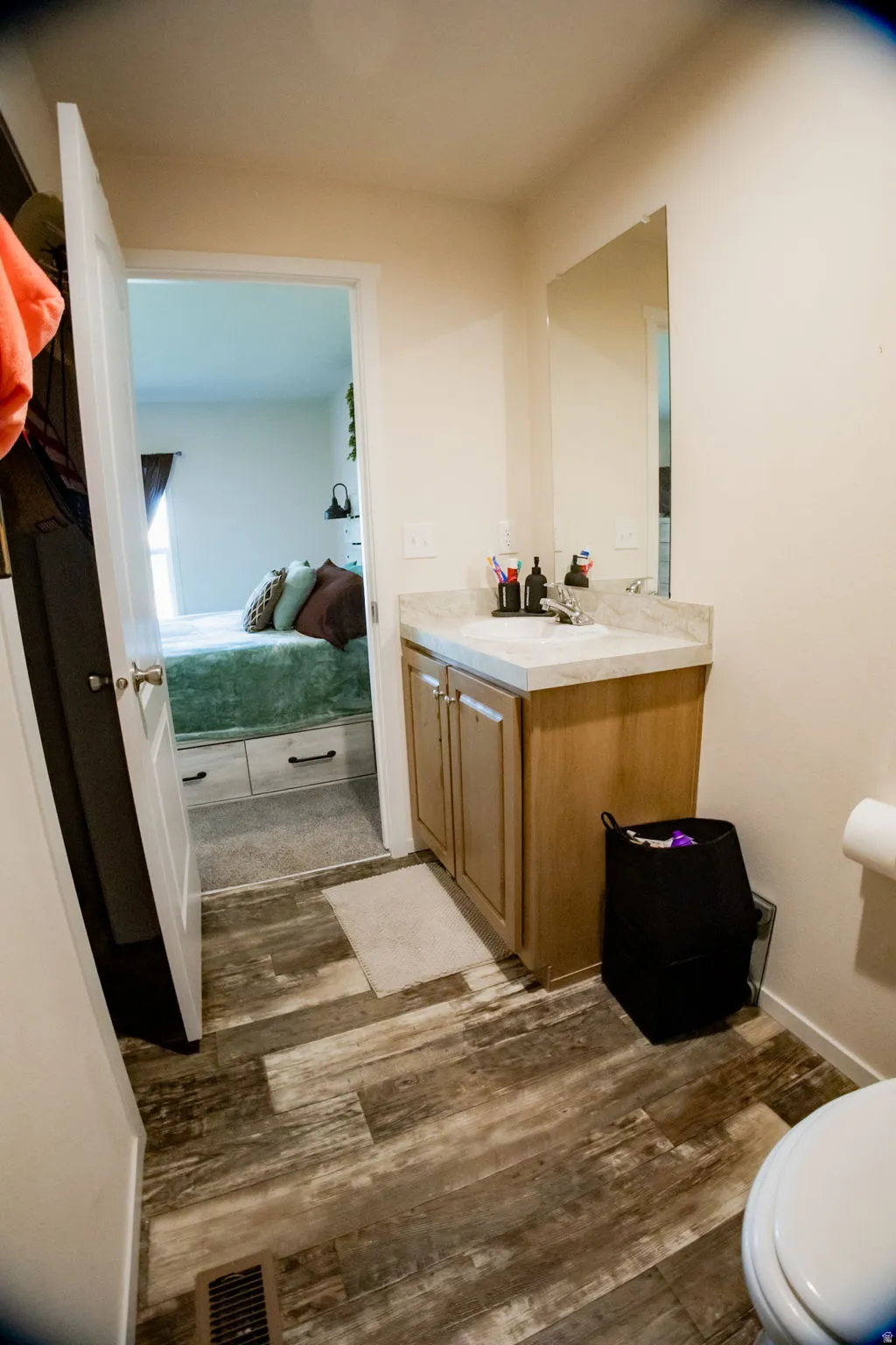 Bathroom featuring wood-finish flooring, a vanity with a light-toned countertop, and a wall-mounted mirror