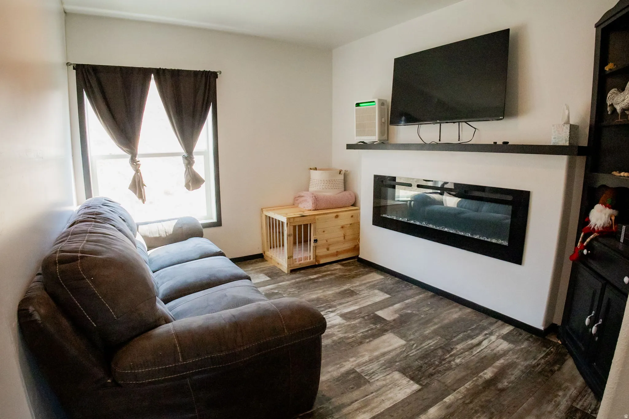 Contemporary living area featuring wood-finish flooring and a built-in electric fireplace with a dark mantel