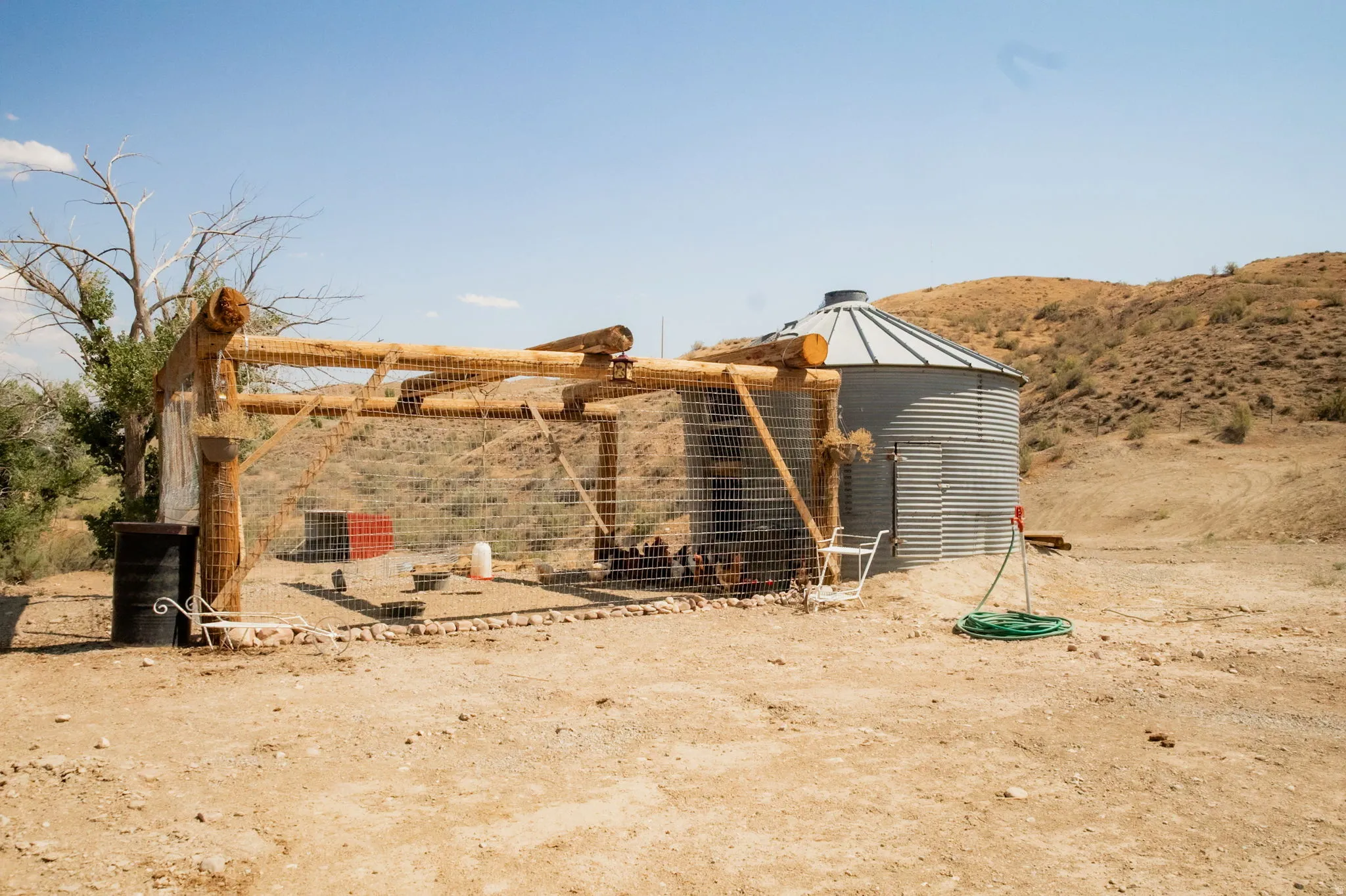 Corrugated metal grain silo with a conical roof and a timber-framed, fenced enclosure