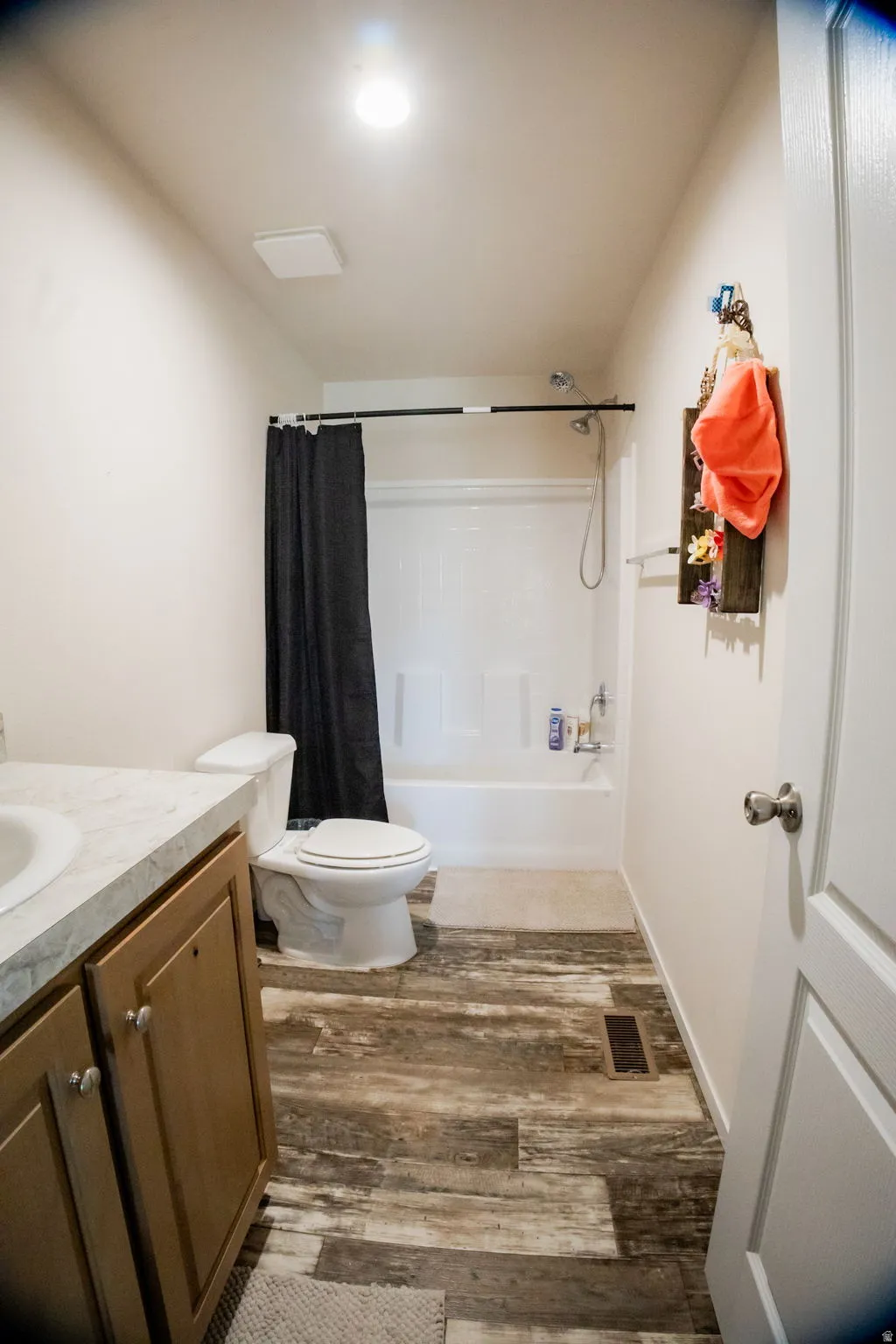 Bathroom featuring wood-finish flooring and a white bathtub with shower