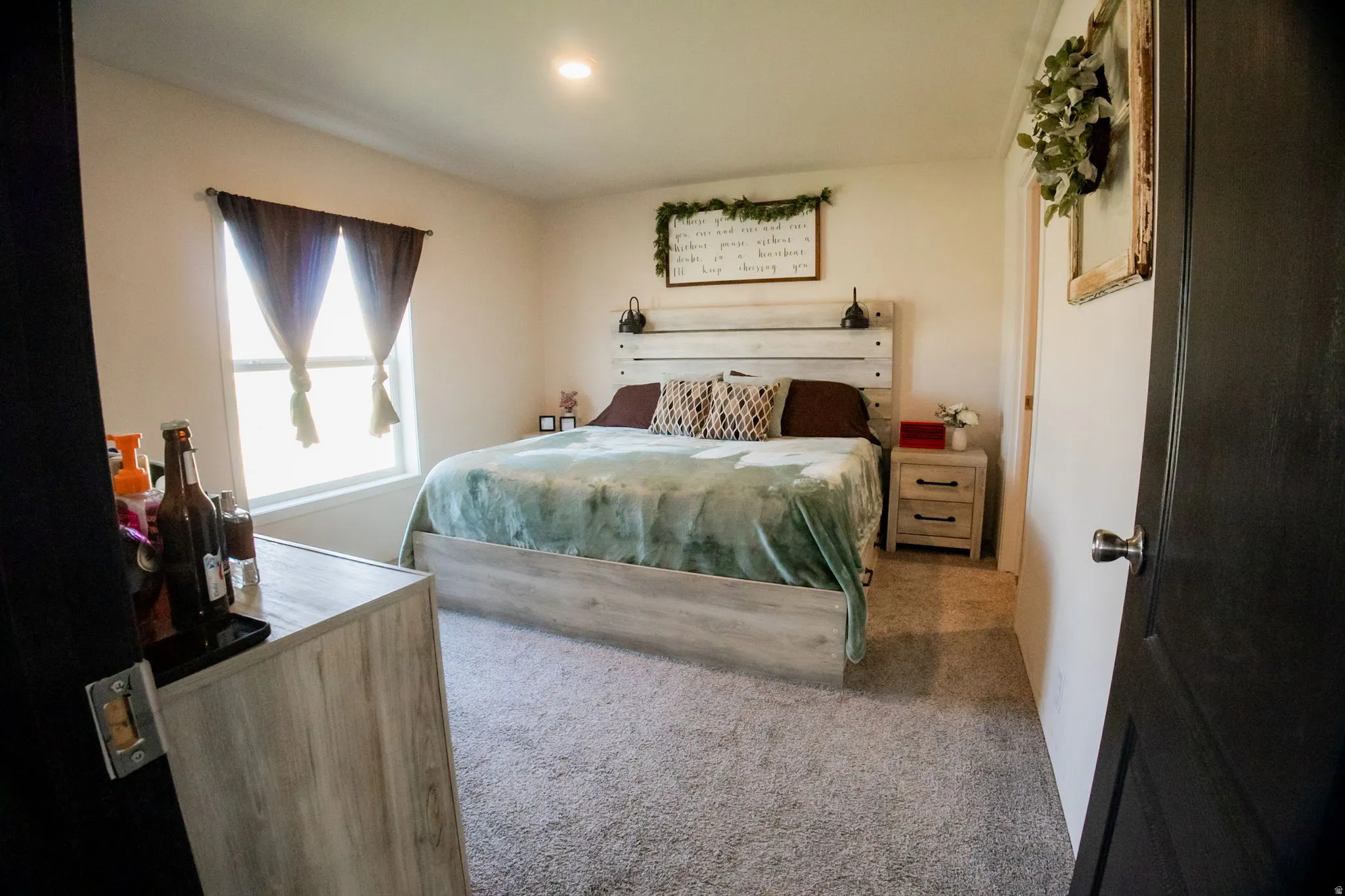 Carpeted bedroom featuring a large window with drapes, recessed lighting, and light-toned walls