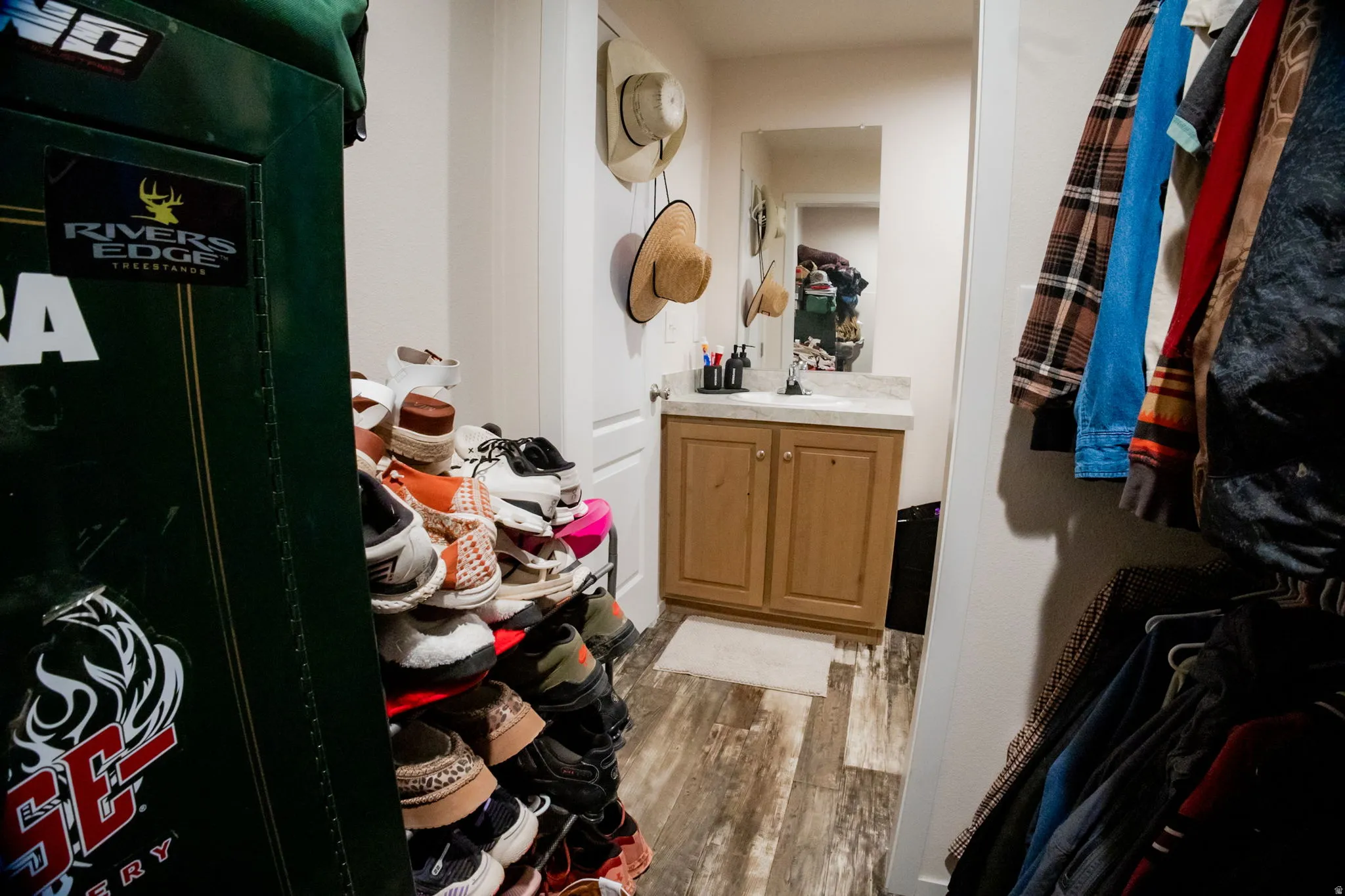 Bathroom featuring a wood-finish vanity with countertop, wall-mounted mirror, and wood-finish flooring