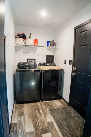 Dedicated laundry space featuring wood-finish flooring, white walls, and a black paneled door