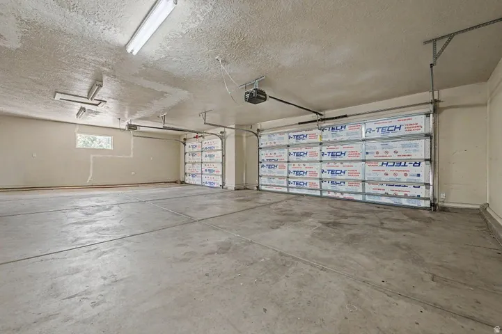 Spacious garage featuring two overhead garage doors, concrete flooring, and fluorescent lighting fixtures