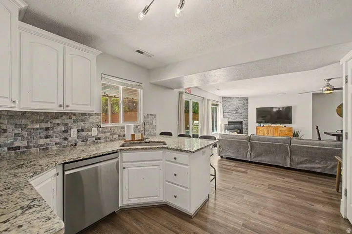 Kitchen with white cabinetry, granite countertops, and a tiled backsplash