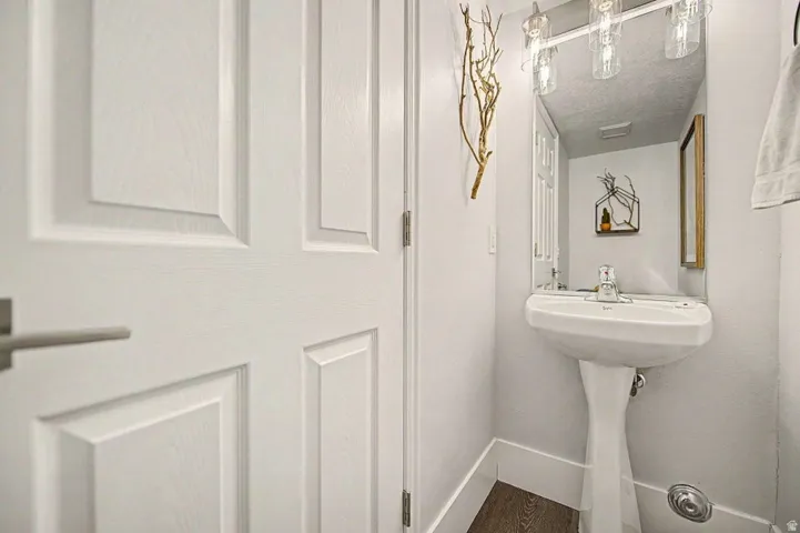Pedestal sink with chrome faucet, large vanity mirror, and three-light fixture