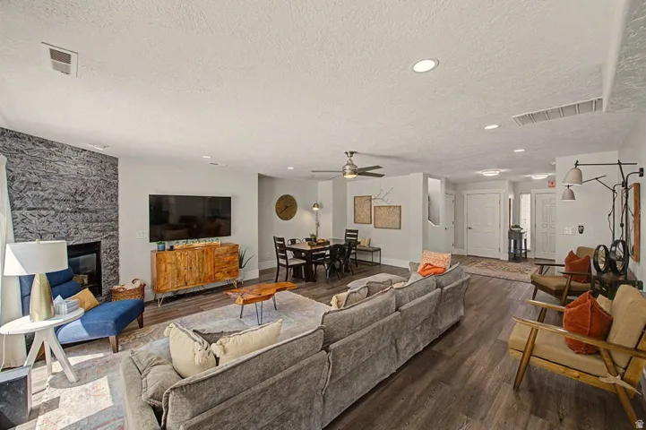 Open-concept living space featuring wood-finish flooring, recessed lighting, and a stone-accented fireplace
