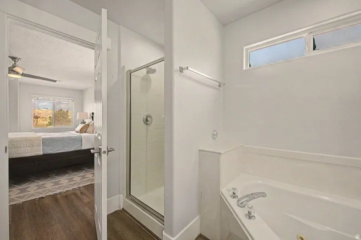 Bathroom featuring a walk-in shower with glass enclosure, corner soaking tub, and a high-set horizontal window
