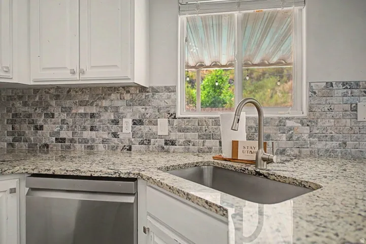 Stainless steel kitchen sink with a high-arc faucet, set within a speckled countertop