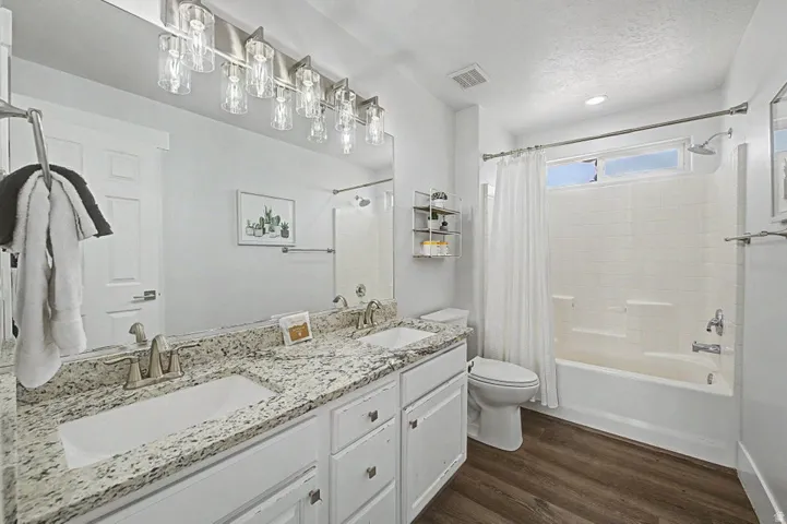 Bathroom featuring a double vanity with granite-style countertops, under-mount sinks, and brushed nickel fixtures