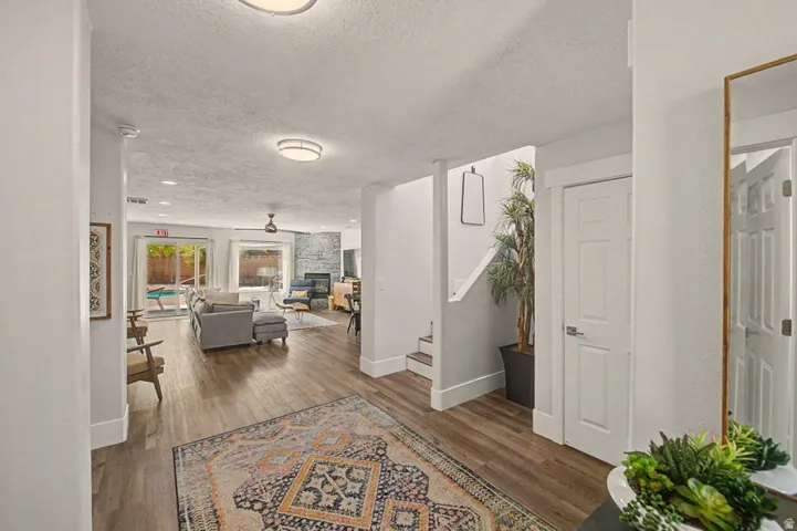 Entryway featuring wood-finish flooring, leading into an open-concept living space with a fireplace