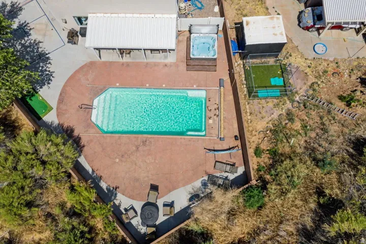 Expansive outdoor area featuring a rectangular pool with integrated steps, a hot tub, and a covered patio