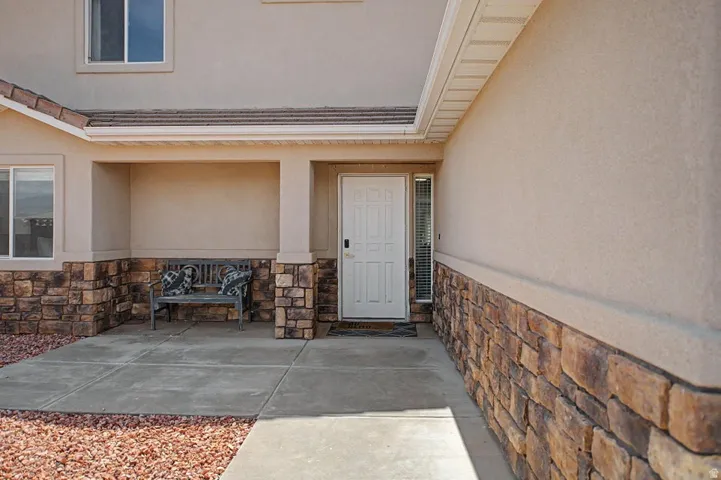 Stucco exterior with a stacked stone facade, covered entry, and white paneled door