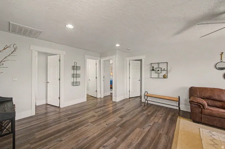 Expansive interior space featuring wood-finish flooring, white walls, multiple doorways, a ceiling fan, and recessed lighting