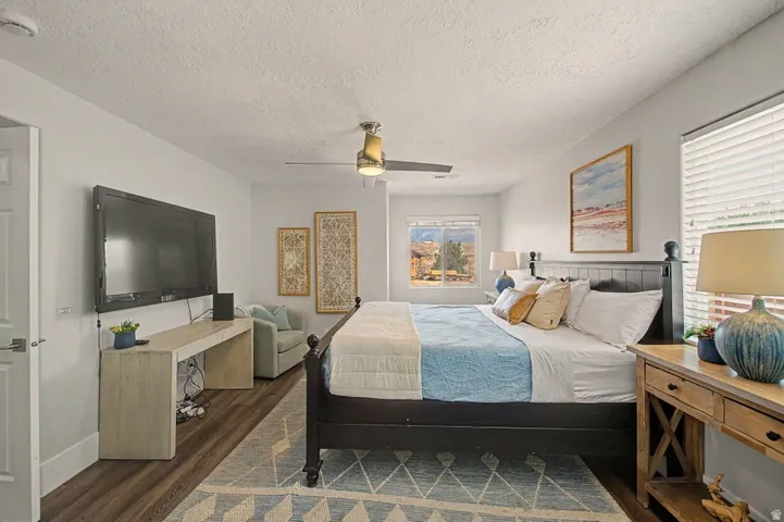 Spacious bedroom featuring wood-finish flooring, a ceiling fan, and multiple windows
