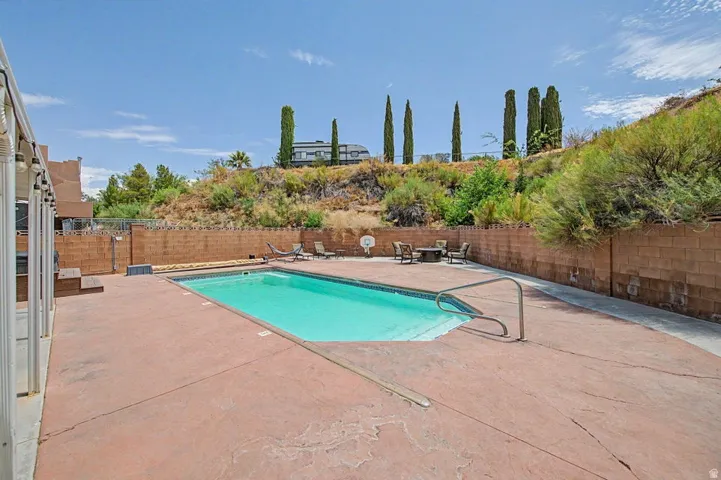 In-ground swimming pool featuring a concrete deck and metal handrail