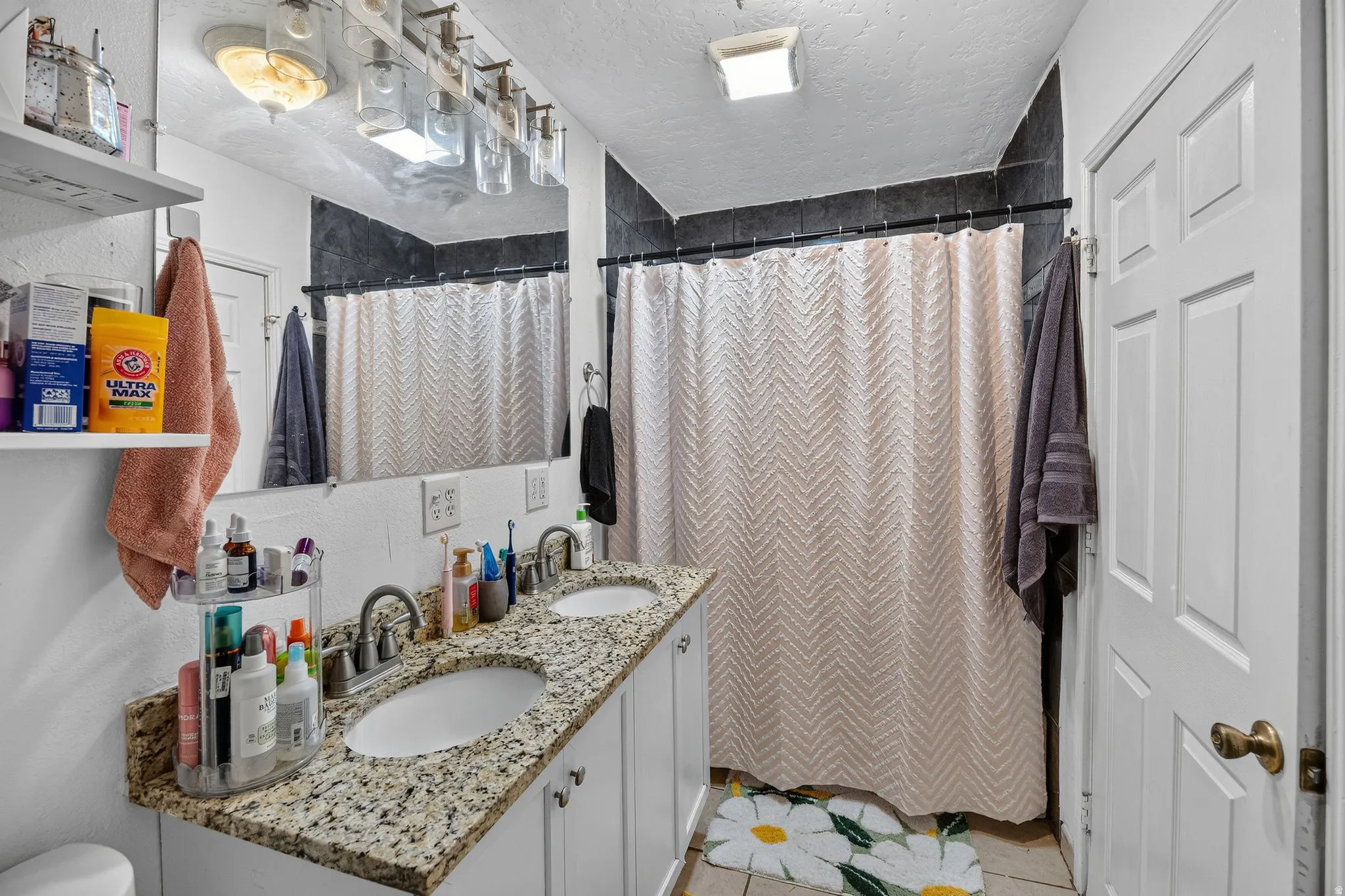 Bathroom featuring a dual vanity with a granite-finish countertop, undermount sinks, and white cabinetry