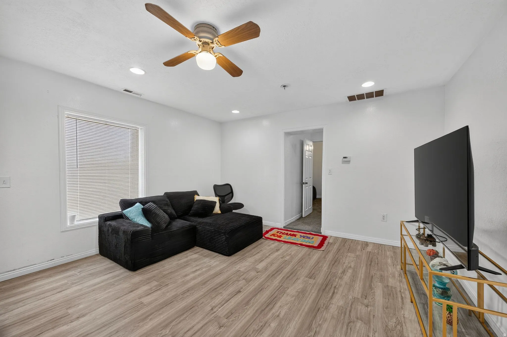 Living area featuring wood-finish flooring, white walls, and a recessed lighting package