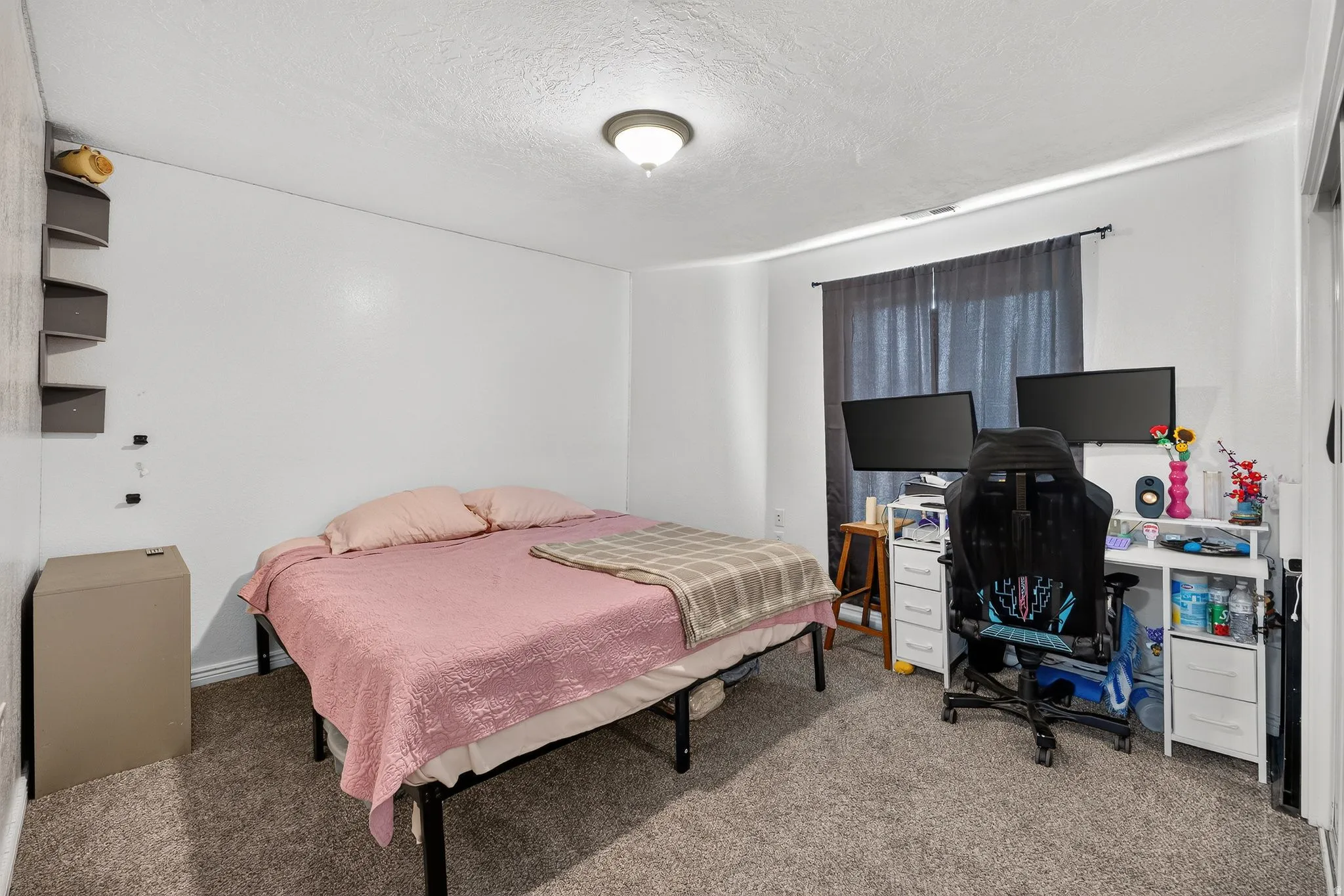 Carpeted room featuring white walls, a single window with dark curtains, and an overhead flush-mount light fixture