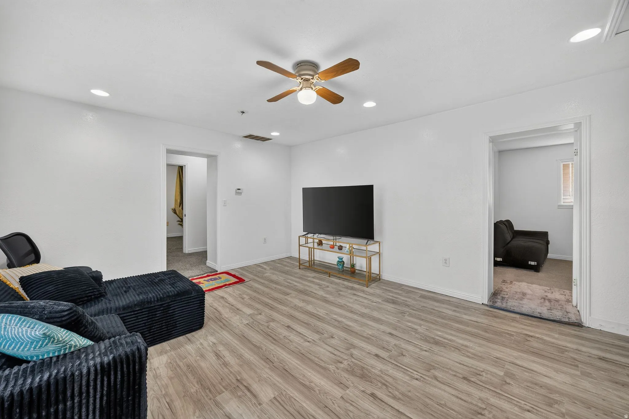 Spacious living area featuring wood-finish flooring, recessed lighting, and a ceiling fan with light fixture