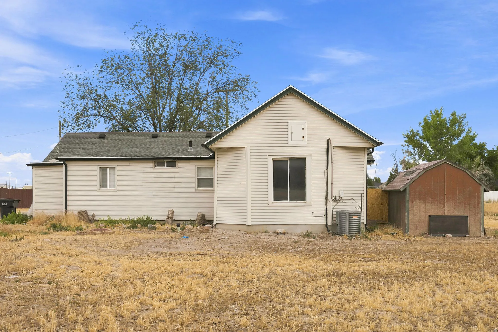 Rear exterior of property featuring light-colored horizontal siding and a dark-shingled roof