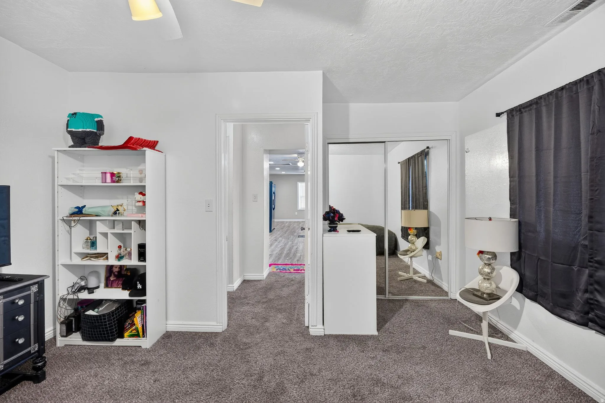 Carpeted room featuring a ceiling fan with light fixture, white trim, and a mirrored closet