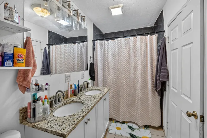 Bathroom featuring a dual vanity with a granite-finish countertop, undermount sinks, and white cabinetry