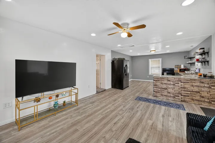 Spacious living area featuring wood-finish flooring, recessed lighting, and a ceiling fan