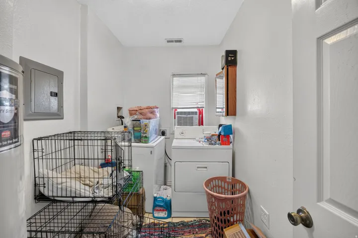 Dedicated laundry area featuring a window with blinds, a wall-mounted electrical panel, and ample space for appliances