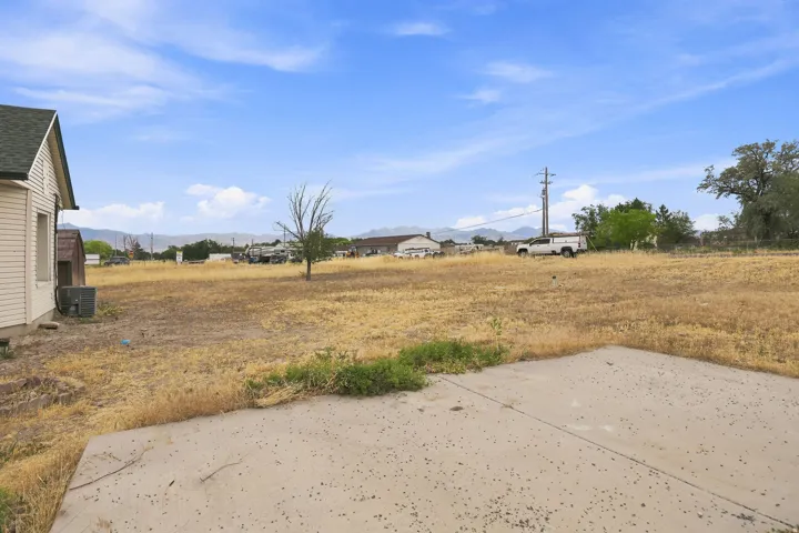 Expansive outdoor space featuring a concrete patio pad, a large open field, and distant mountain scenery