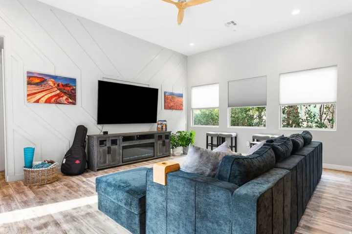 Living area featuring high ceilings, wood-finish flooring, and a decorative accent wall with geometric paneling