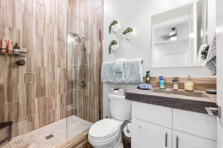 Contemporary bathroom featuring a walk-in glass shower with wood-finish tile surround and a white hexagonal tile floor