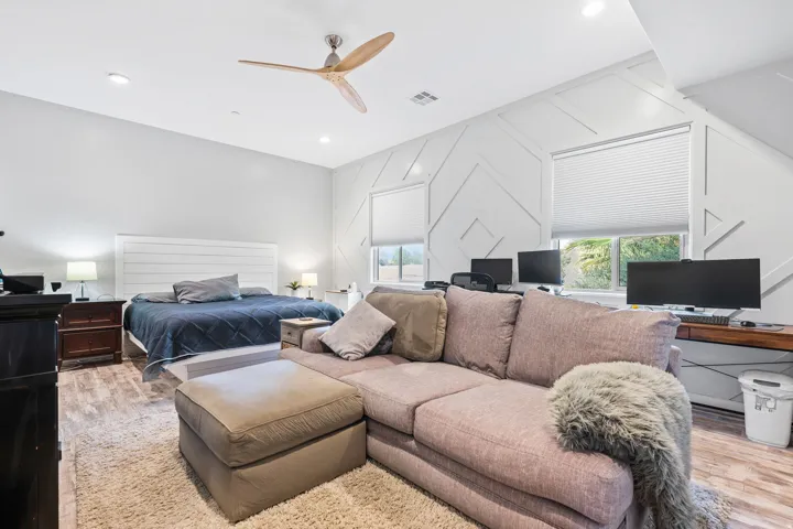 Spacious room featuring wood-finish flooring and a white shiplap headboard