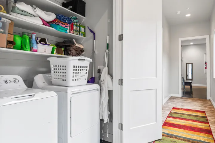 Dedicated laundry area featuring stacked appliances and built-in shelving