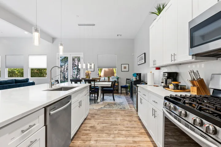 Contemporary kitchen featuring white cabinetry, light-toned countertops, stainless steel appliances, and wood-finish flooring