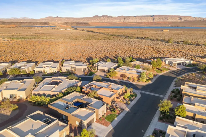 Aerial view of a residential community featuring flat-roofed homes, paved streets, and a desert landscape