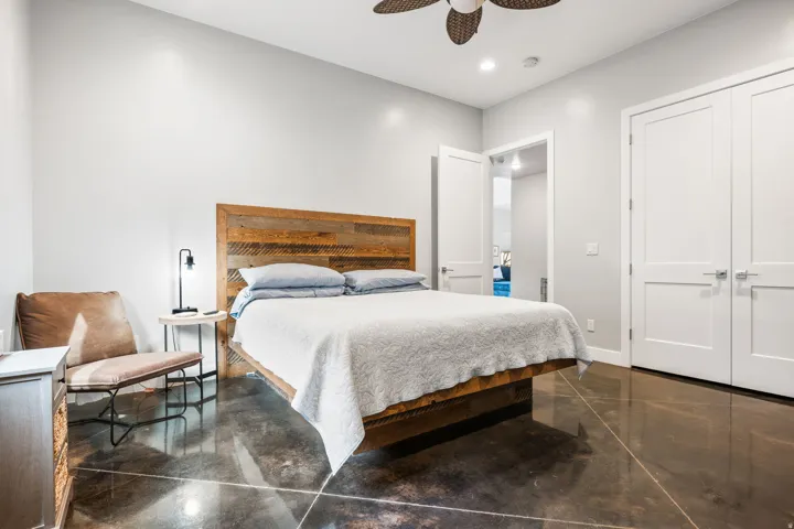 Spacious bedroom featuring polished concrete flooring, white paneled doors, and recessed lighting