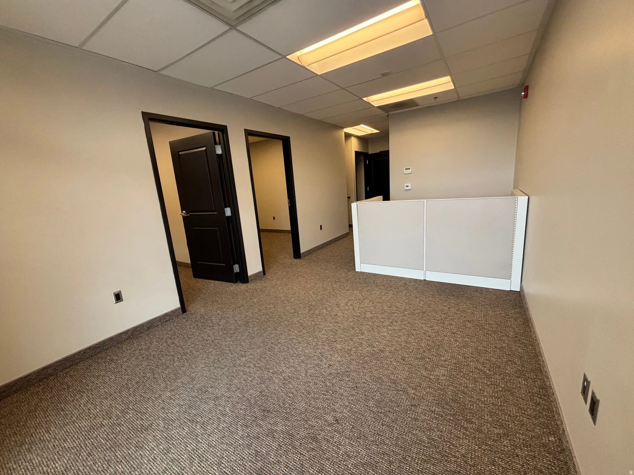Office space featuring textured carpet flooring and neutral wall tones
