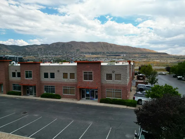 Commercial building featuring multi-toned brick and stone facade, multiple large windows, and an expansive paved parking area