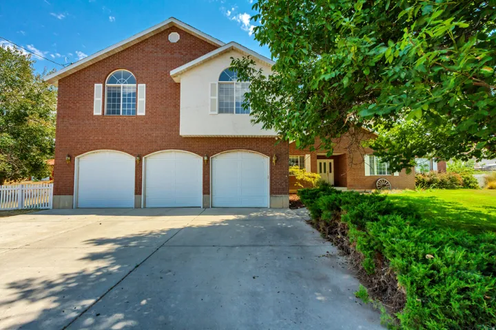 Brick exterior with a three-car garage, white arched garage doors, and a concrete driveway