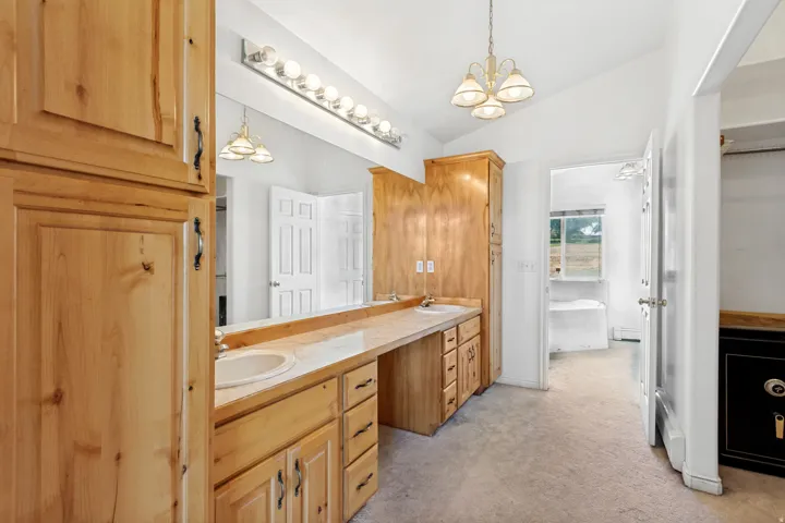 Bathroom featuring natural wood cabinetry, a dual vanity with integrated sinks, and an extended countertop