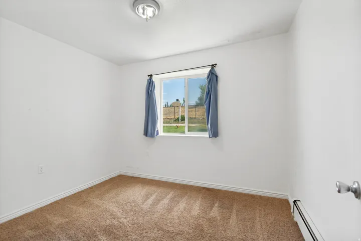Room featuring a single pane window, neutral carpet, white baseboards, and a semi-flush mount ceiling light